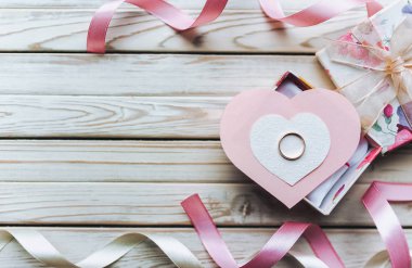 Evlilik teklifi kavramı. Ahşap arka plan üzerinde bir hediye kutusunda bir nikah yüzüğü. Sevgililer günü. Kopya alanı.