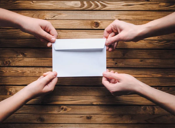 The white envelope is in the hands of two people. Salary in the envelope. The concept of the letter.