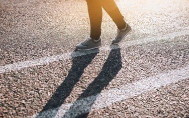 Asfalt yolda günbatımında çalışan fitness kadın. Beyaz çizgi. Yakın çekim.