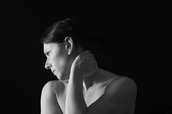 Mulher de meia-idade com dor no pescoço em fundo preto — Fotografia de Stock