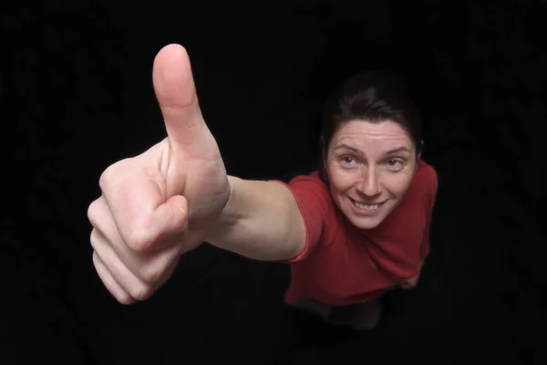 Woman with thumbs up on black — Stock Photo, Image