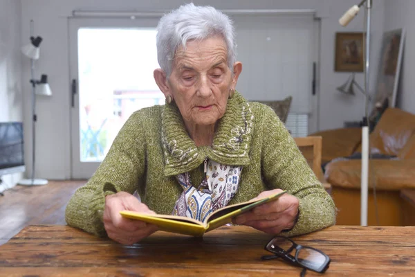 Senior kvinna läser en bok hemma — Stockfoto
