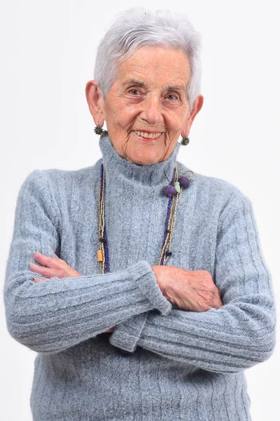 Senior kvinna med armar korsade på vit bakgrund — Stockfoto