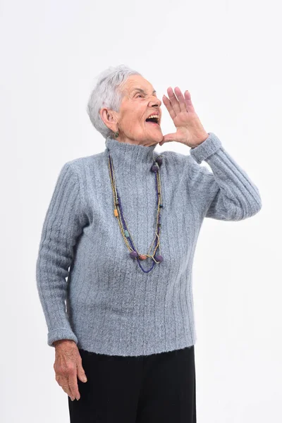 Senior kobieta kładąc rękę w ustach i krzyczy na b biały — Zdjęcie stockowe