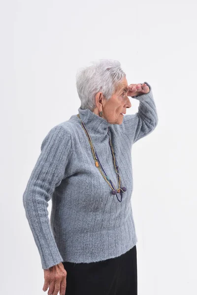 Senior vrouw met hand op de voorgrond op zoek weg op witte achtergrond — Stockfoto