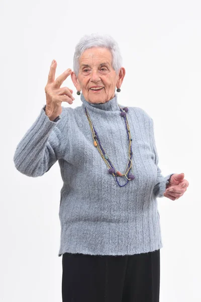 Oudere vrouw maken de overwinning ondertekenen op een witte achtergrond — Stockfoto