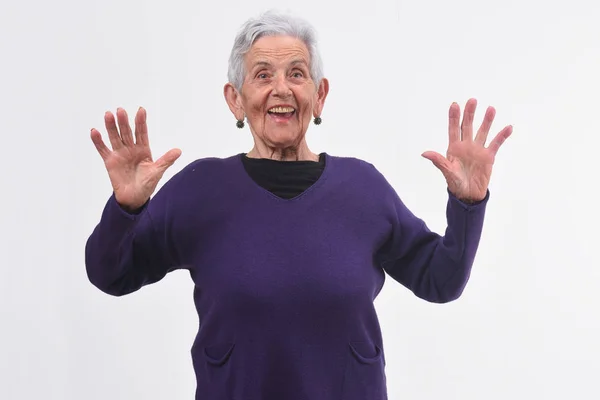 Senior vrouw met een verbaasd gezicht en verhoogde handen op witte bac — Stockfoto