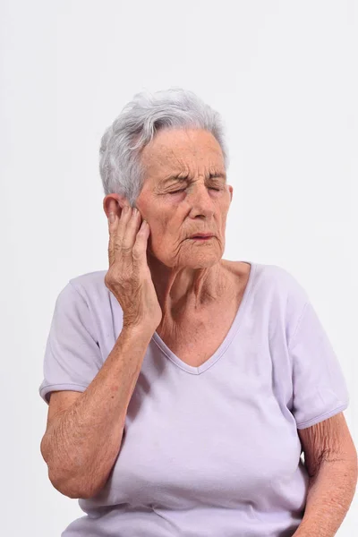 Mujer mayor con dolor en la oreja sobre fondo blanco —  Fotos de Stock