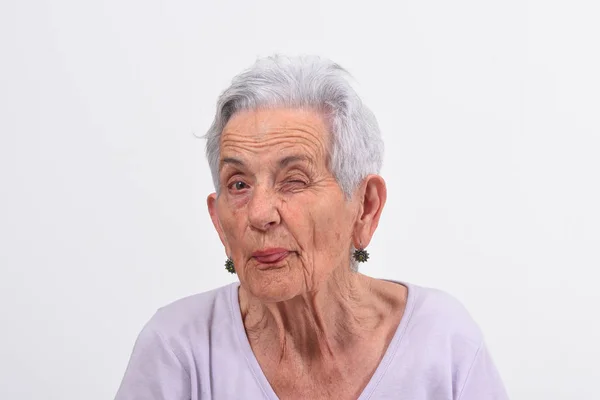 Seniorin zwinkert auf weißem Hintergrund — Stockfoto