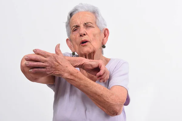 Seniorin mit Schmerzen am Ellbogen auf weißem Hintergrund — Stockfoto