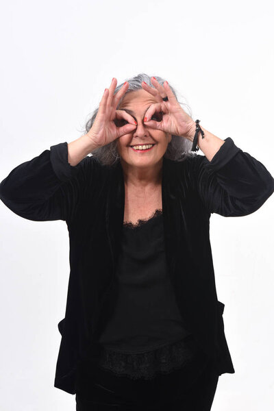 Senior woman looking through fingers as if wearing glasses on wh
