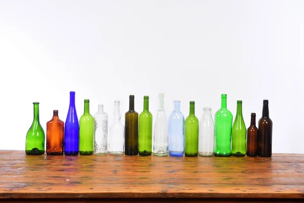 Flera flaskor ovanpå ett träbord med vit bakgrund — Stockfoto