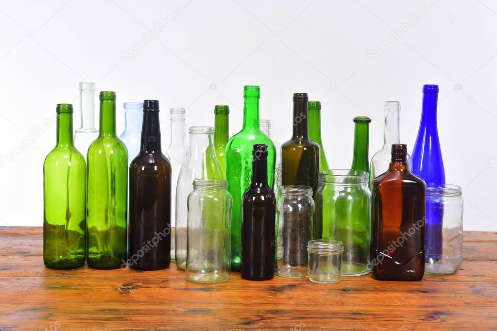 group of bottles and glass jars on a wooden table with white bac