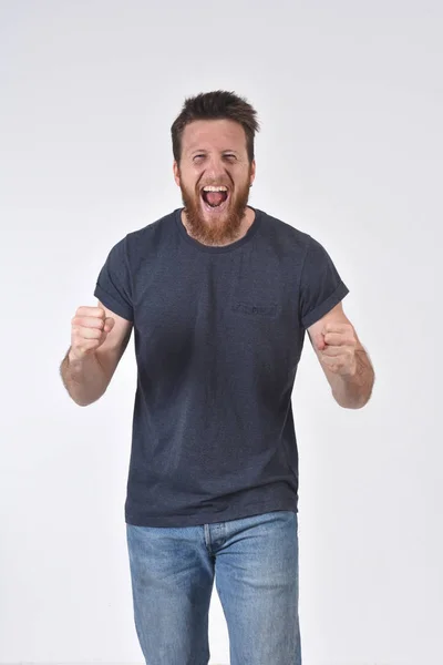 Hombre levantando sus brazos y sonriendo en señal de victoria sobre fondo blanco — Foto de Stock