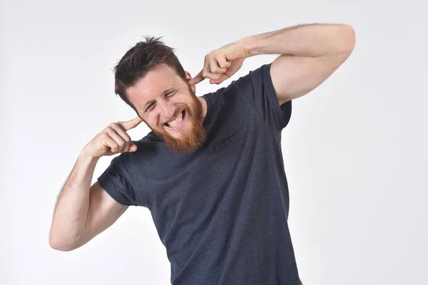 Homem fazendo barulho machucando seus ouvidos no fundo branco — Fotografia de Stock