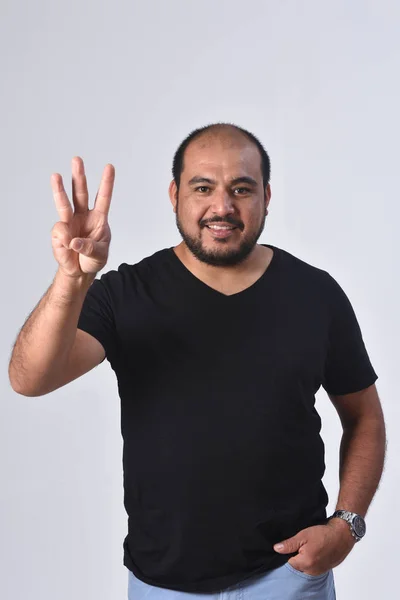 Hombre latino con el dedo en la forma del número 3 —  Fotos de Stock