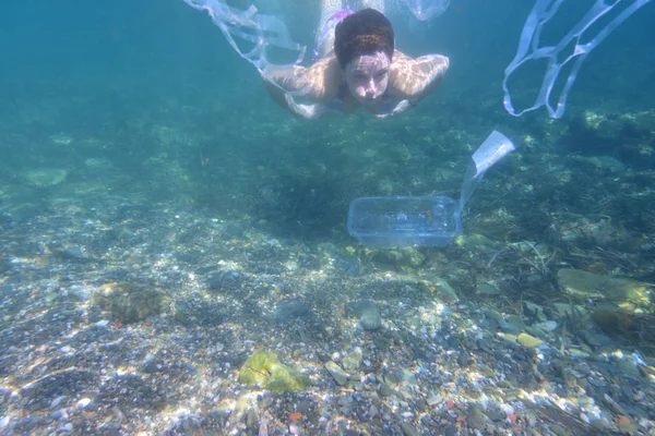 Mujer buceando en el mar con basura —  Fotos de Stock