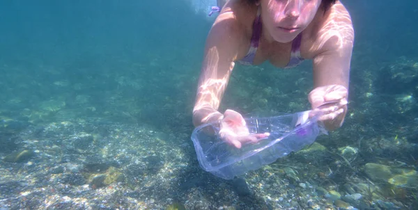 woman picking up garbage, plastic, from the bottom of the sea