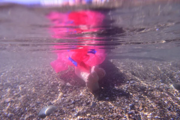 Kvinna med fötter på stranden och plast — Stockfoto