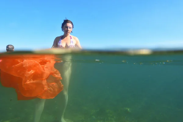 Kvinna som badar i havet med plast i vattnet — Stockfoto