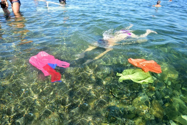 Vrouw duiken in de zee met vuilnis — Stockfoto