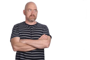 Kollarını kavuşturup beyaz arka plana bakan bir adamın portresi.