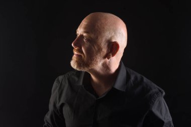 Gösterişsiz bir adam portresi, gülümsüyor ve yukarı bakıyor.