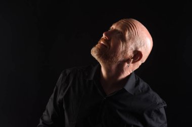 Gösterişsiz bir adam portresi, gülümsüyor ve yukarı bakıyor.