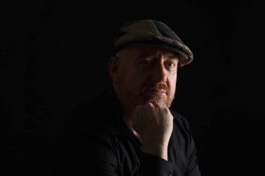 Gösterişsiz bir adam portresi, kameraya bakıyor.