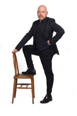 Takım elbiseli adam beyaz arka planda sandalyeyle oynuyor.