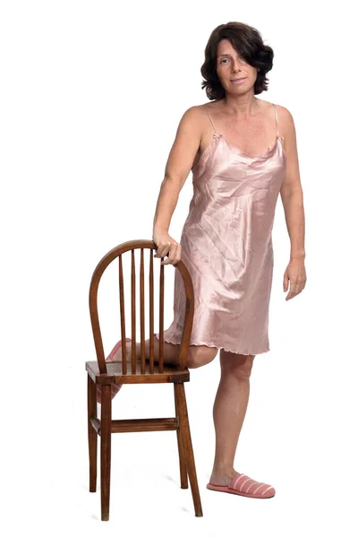 一个穿着白色背景睡衣的女人坐在椅子上玩耍的镜头 — 图库照片