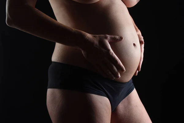 黑色背景下的孕妇肚脐闭合 — 图库照片