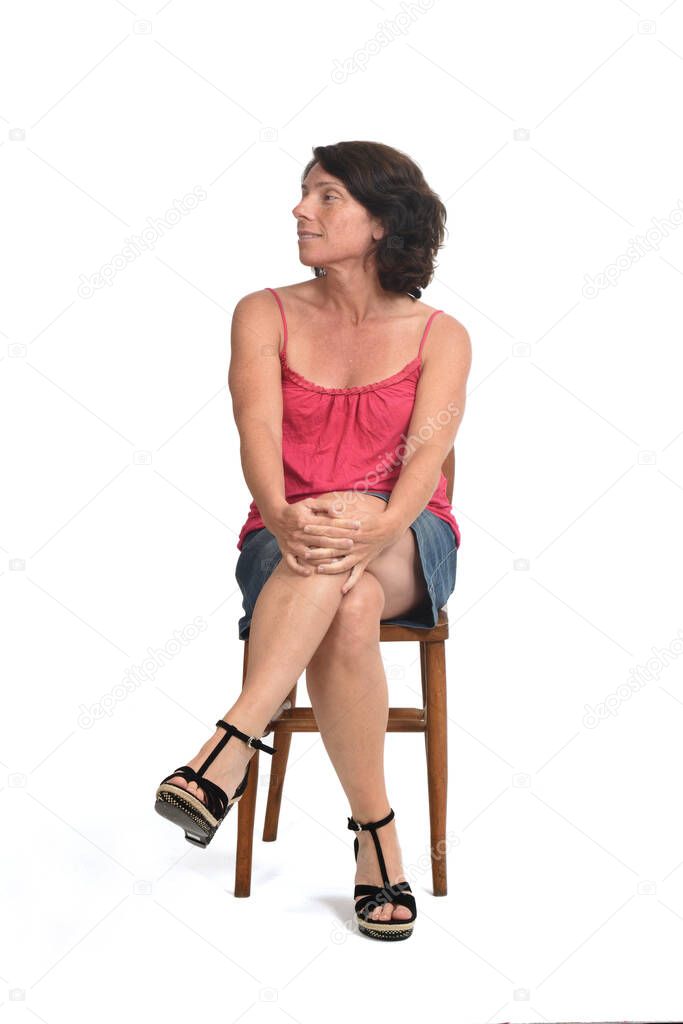 woman in skirt sitting on white background, look side
