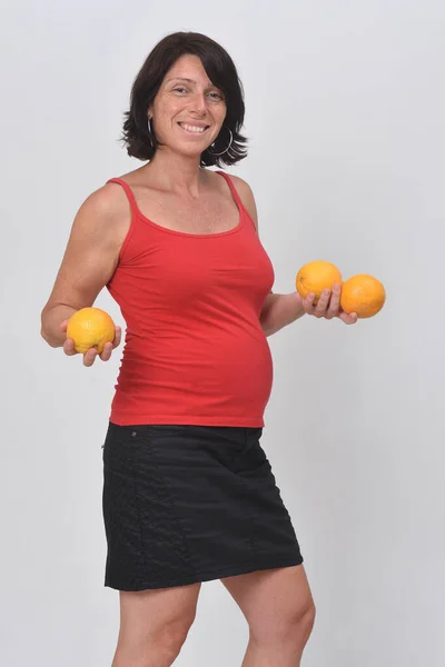 Mujer Embarazada Sosteniendo Una Fruta Naranja Sobre Fondo Blanco — Foto de Stock