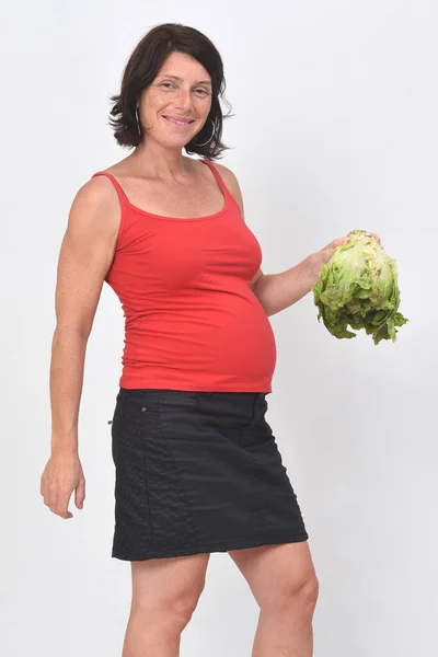 妊娠中の女性は白い背景にレタスを持ち — ストック写真