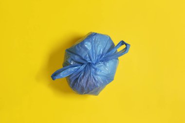 Sarı arkaplanda kapalı mavi bir çöp torbasının üst görünümü