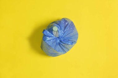 Sarı arkaplanda kapalı mavi bir çöp torbasının üst görünümü