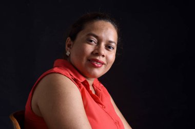 Siyah arka planda ön planda gülümseyen bir kadının portresi