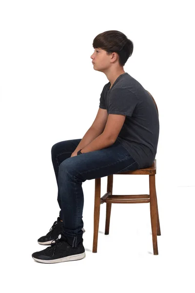 Dospívající Chlapec Sedí Židli Bílým Pozadím Podívejte Stranou — Stock fotografie