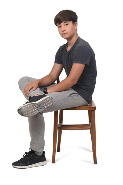 侧视青少年男孩坐在白色背景的椅子上 看着相机 — 图库照片