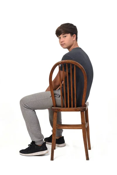 Side View Teenage Boy Sitting Chair White Background Looking Camera — стоковое фото