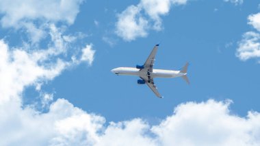 Bulutların üzerinde uçan beyaz yolcu uçağı. Gökyüzünde uçan uçak görüntüsü. Ulaşım, tatil, turizm ve seyahat konsepti fotoğrafı.. 