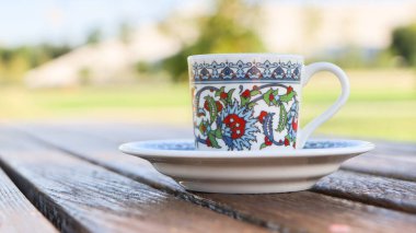 Türk kahvesi (Türk kahvesi). Parktaki bir masada fayans desenli porselen Türk kahve fincanı..