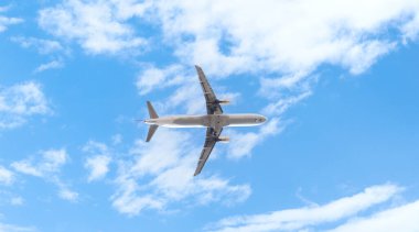 Güzel mavi gökyüzünde iniş takımları açık uçan büyük yolcu uçağının alt görüntüsü..