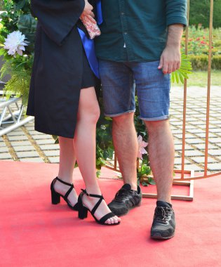 Öğrenci, mezuniyet kıyafetiyle, arkadaşları ve ailesiyle birlikte unutulmaz grup fotoğrafları için dışarıda poz veriyor.