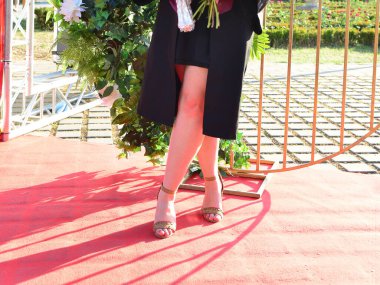 Kendinden emin öğrenci modelleri açık havada şık topuklu ayakkabılar ve seremoni sırasında zarif bacaklar giyerler.