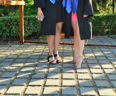 Kendinden emin öğrenci modelleri açık havada şık topuklu ayakkabılar ve seremoni sırasında zarif bacaklar giyerler.