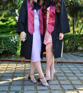 Kendinden emin öğrenci modelleri açık havada şık topuklu ayakkabılar ve seremoni sırasında zarif bacaklar giyerler.