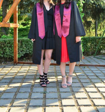 Kendinden emin öğrenci modelleri açık havada şık topuklu ayakkabılar ve seremoni sırasında zarif bacaklar giyerler.