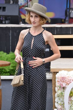 Timisoara, Romanya, 24 Haziran 2018, çanta ve gri şapkalı zarif kadın, yardım amaçlı opera fuarı başlamadan önce kuliste güven içinde poz veriyor.